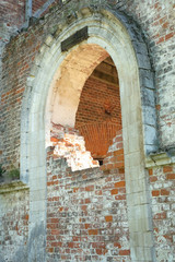 Arch, partially laid bricks in the wall of old destroyed Christian church