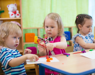 Kids or children creating arts and crafts in kindergarten. Girl is communicating with boy.