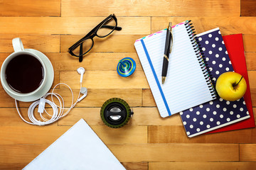 Notebooks, pen, glasses, apple on a wooden
