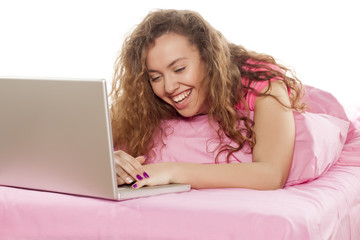 Happy girl looking at her laptop on the bed