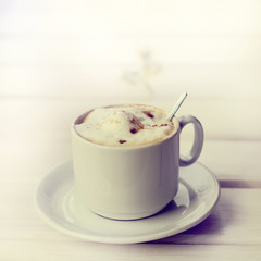 retro coffee/ frothy cappuccino with cinnamon in a white mug and spoon 