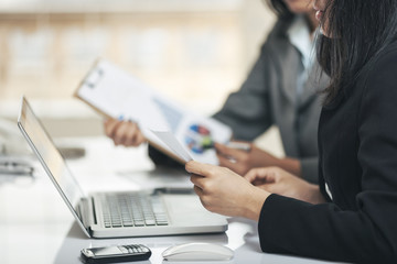 businesswomen comparing the graphical documents with the docs on the laptop 
