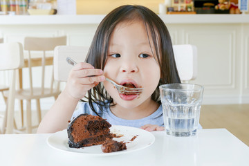 Little asian girl eating chocolate cake