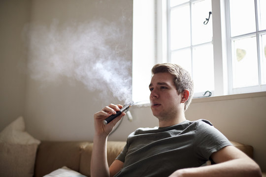 Young Man Using Vapourizer As Smoking Alternative