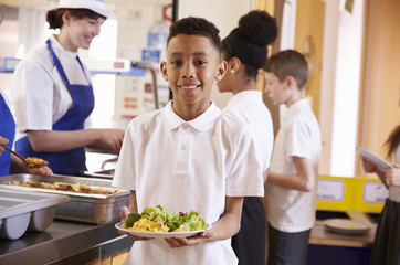 Mixed race boy holding a plate of food in a school cafeteria