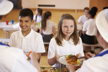 Over shoulder view of kids being served in school cafeteria