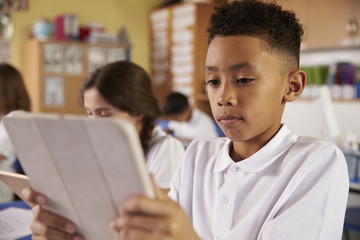 Mixed race primary school boy using tablet computer in class © Monkey Business
