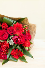 Closeup shot of red bouquet of roses, gerberas, peonies, pomegranates with copyspace. Love and passion symbol. Anniversary gift. Birthday present for girl.
