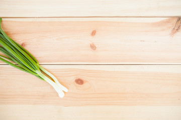 Green onion on light wooden background with copyspace.