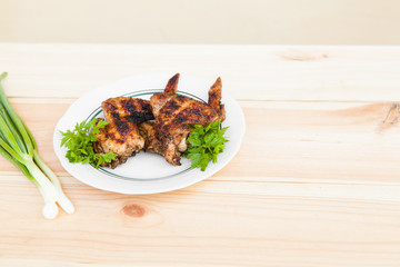 Chicken wings on plate and onion on light wooden background with copyspace. Cuisine background. Eastern food. Street food. Weekend barbeque.