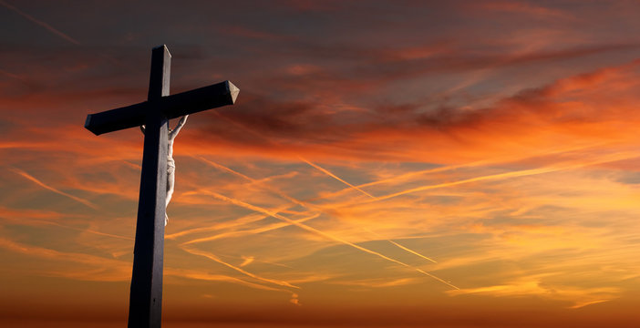 Christian cross over sunset background