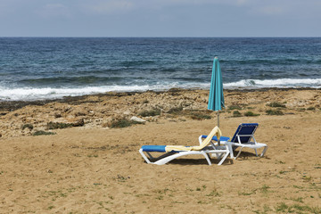 Fototapeta na wymiar Sunbeds and straw umbrella for relaxation on the sea beach