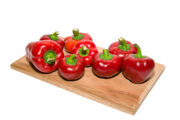 Several  peppers on a wooden cutting board.