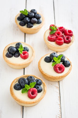 Delicious tartlets with raspberries and blueberries
on white wood