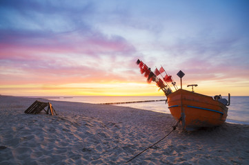 Zachód słońca nad morską plażą,kutry rybackie na piasku