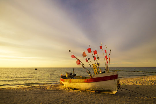Fototapeta Zachód słońca nad morską plażą,kutry rybackie na piasku