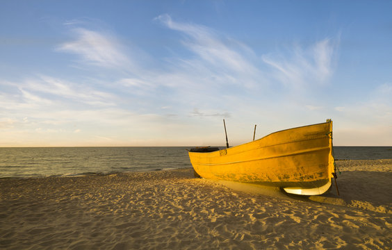 Fototapeta Zachód słońca nad morską plażą,kutry rybackie na piasku