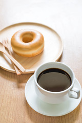 Coffee and donut in wooden dish blurred background