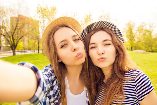 Two beautiful girls in caps making selfie and pouting