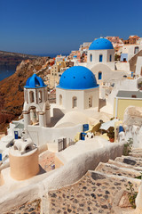Landscape of Oia town in Santorini, Greece with blue dome churches and stairs on foreground.