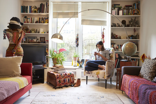 Woman Relaxing Using Mobile Phone In Stylish Apartment