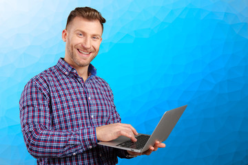 Young man standing, holding laptop computer, working.