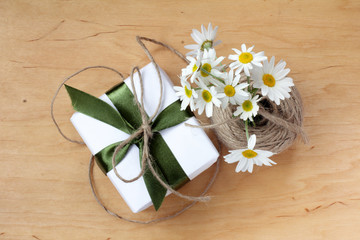 gift with floral spirits/ gift wrapped in green ribbon and a bouquet of daisies 