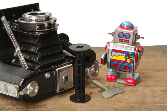 Tin robot toy with Antique Vintage Retro Old Photo Camera compose on wooden plank on white background