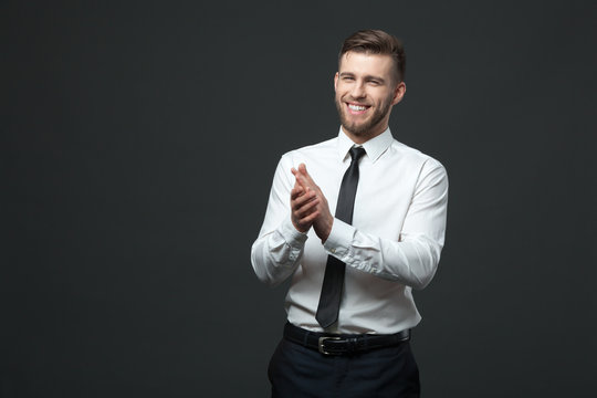 Studio portrait of young happy handsome businessman claping hand