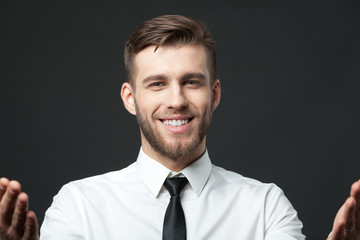 Portrait of young happy businessman isolated on dark gray backgr