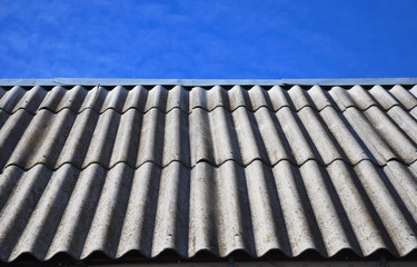 Blue sky over the dangerous asbestos old roof tiles 