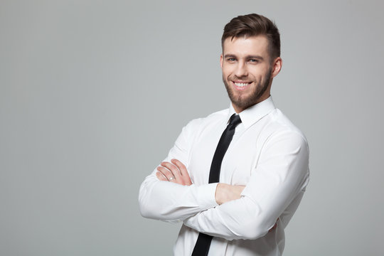 Portrait of handsome young businessman on gray background.