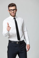 Young handsome businessman pointing at you  isolated on gray bac