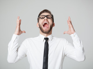 Young businessman screaming -  isolated on gray background.