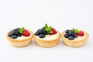 Delicious tartlets with raspberries and blueberries isolated on white background
