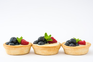 Delicious tartlets with raspberries and blueberries isolated on white background
