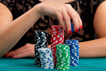 Woman holding gambling chips on green background. Focus on hand holding several blue chips