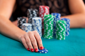 Woman betting gambling chips. Focus on hand.
