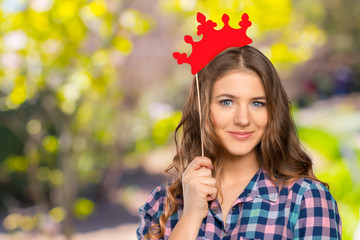 Closeup portrait of beautiful young girl with festive paper crown on her head.