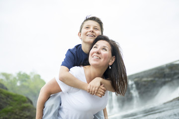 mother and son playing in front of a waterfall