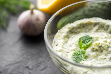 Tzatziki in the glass bowl on the black stone table horizontal