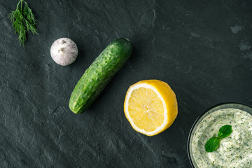 Tzatziki  on the stone table with ingredients top view