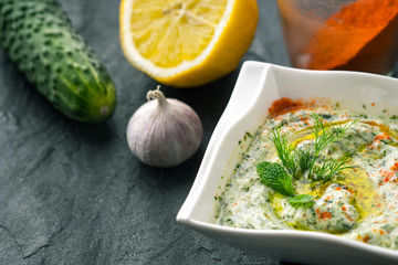 Tzatziki  on the stone table with cucumber , lemon and seasoning horizontal