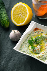 Tzatziki  on the stone table with cucumber , lemon and seasoning vertical