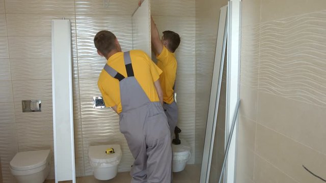 Two Young Workers Are Assembling Partition Walls in Toilet Cubicles. Mounting Works