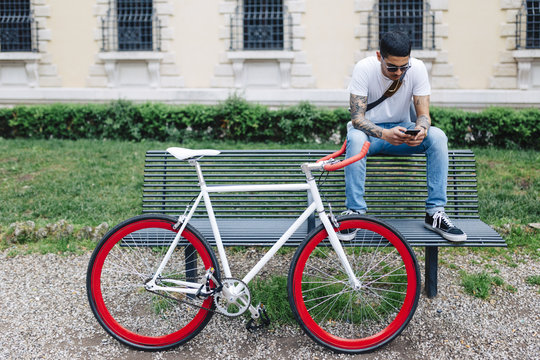 Young man with a bicycle sitting on bench