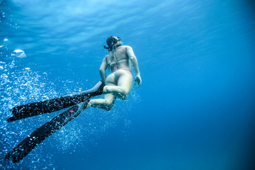 Woman underwater in the ocean with flippers and bubbles. Rear view of the beautiful butt © Fotolia Premium