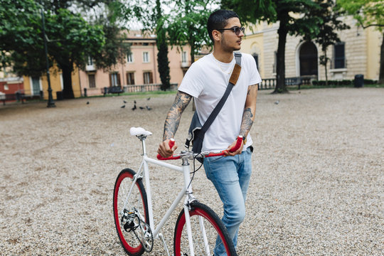 Young man walking with a bicycle in the city