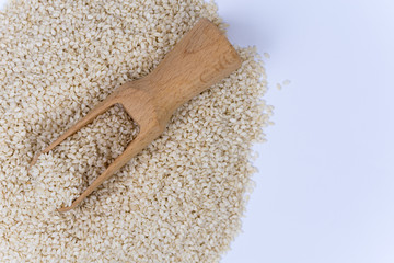 Pile of sesame with wooden spoon isolated over white background