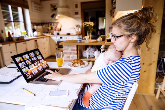 Mother with baby at home working with laptop